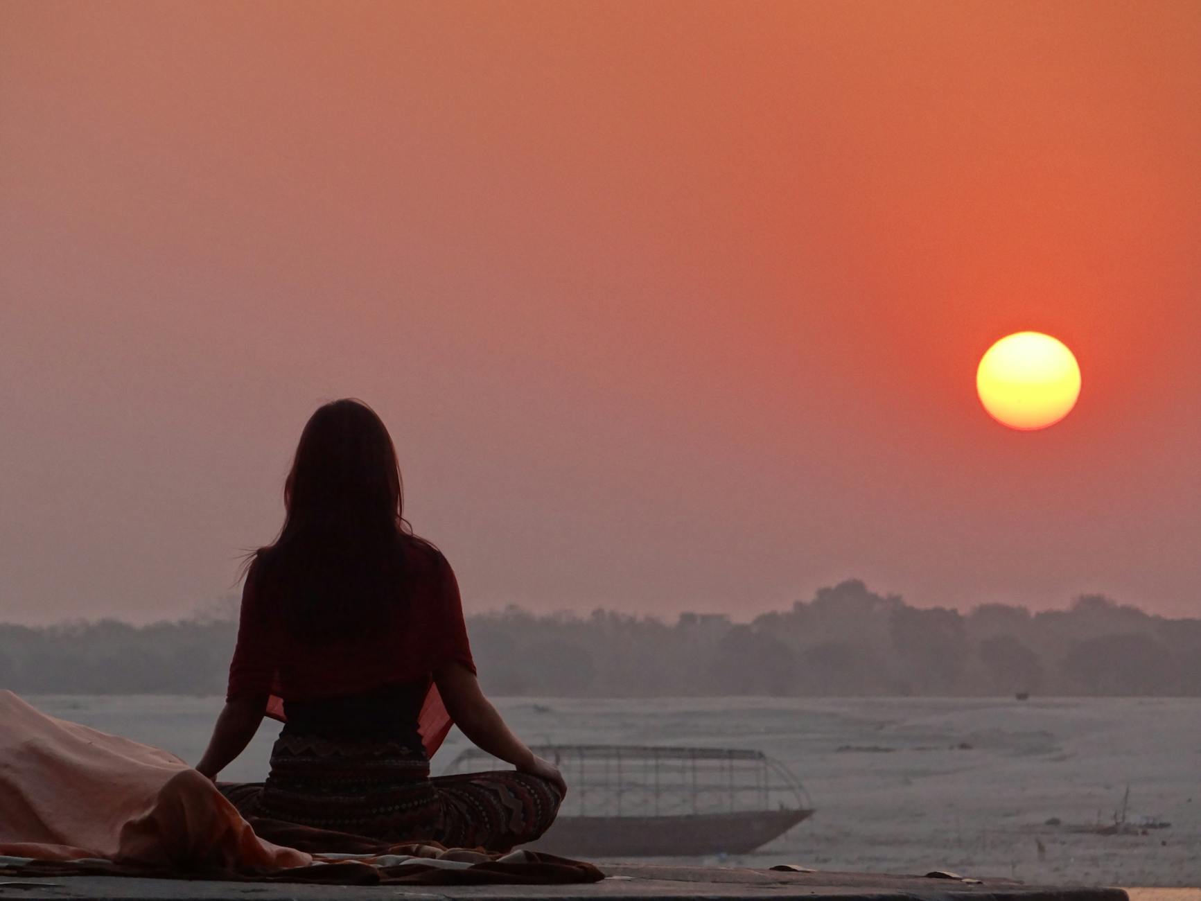 Woman meditating at sunrise representing the foundations and abundance energy of angel number 844