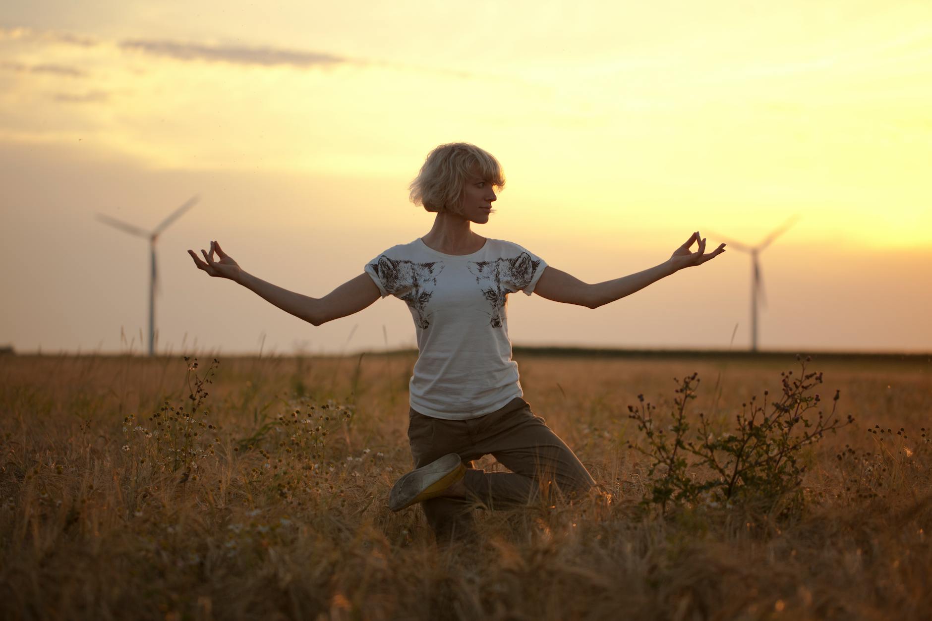 Woman in a peaceful posture at sunrise representing the completion and renewal energy of the 9090 angel number